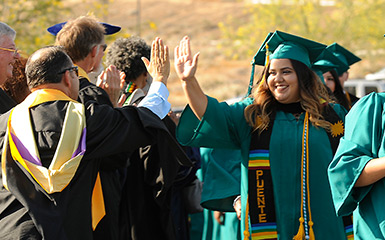 A student and faculty member high five during graduation