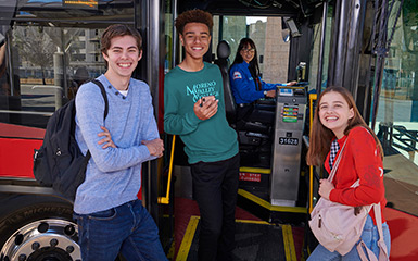 Three students stand at RTA bus