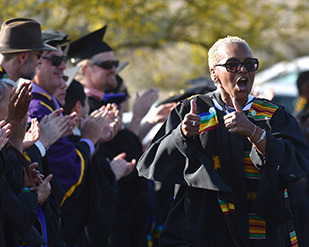 Professor Frankie Moore walks down a line of faculty during Commencement
