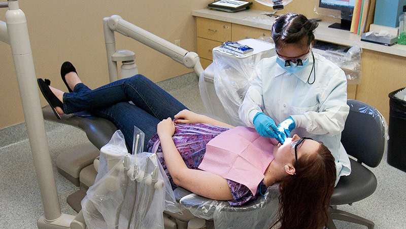 A dental student works on a patient