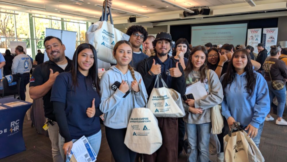 A group of students pose together and hold up their expo souvenir bags