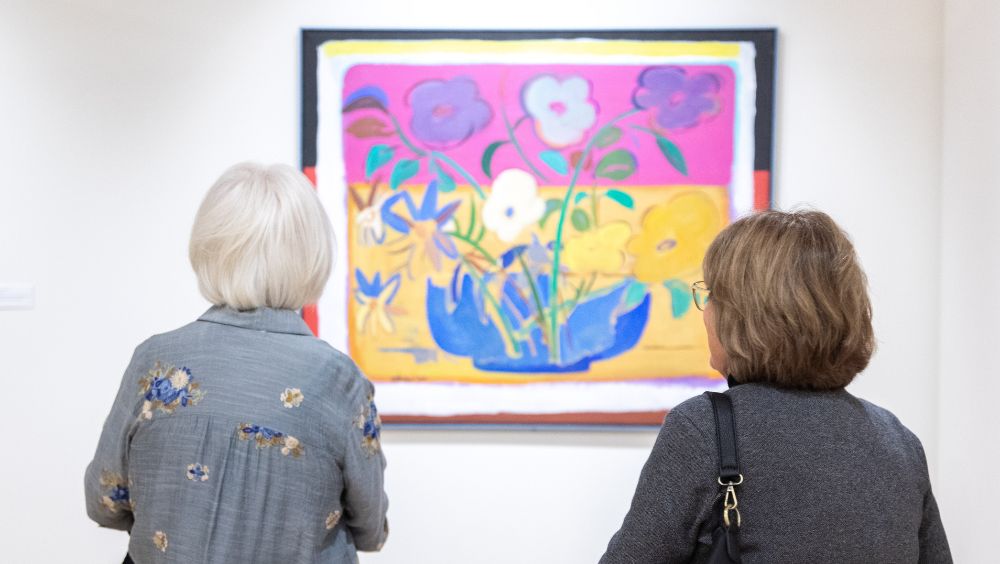 Two individuals look at hanging artwork in a museum