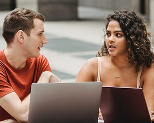 Two students study together at laptops