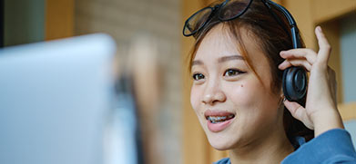 A student chats at a computer while wearing a headset