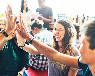 A group of students high five during a workshop