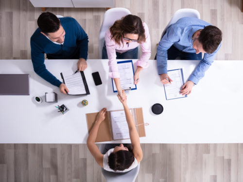 A top-down shot of four people sitting at a conference table during a job interview