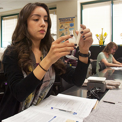 A student holds up a vial in biology class.
