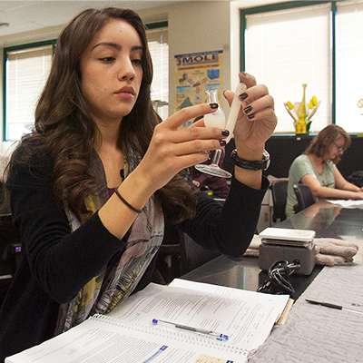 A student holds up a vial in science class