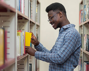 A student pulls a book from the shelves