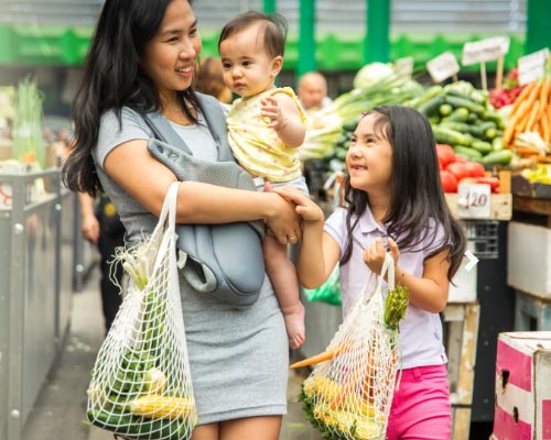 A woman with an infant and young daughter go grocery shopping
